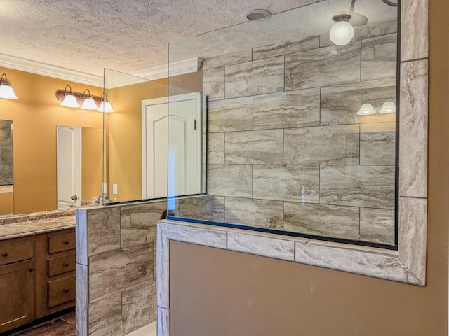 bathroom with crown molding, vanity, a textured ceiling, and walk in shower