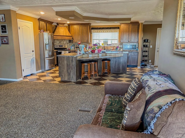 kitchen with a kitchen island, ornamental molding, custom exhaust hood, stainless steel appliances, and light floors