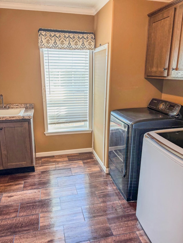 washroom with dark wood-style flooring, washing machine and clothes dryer, cabinet space, ornamental molding, and a sink