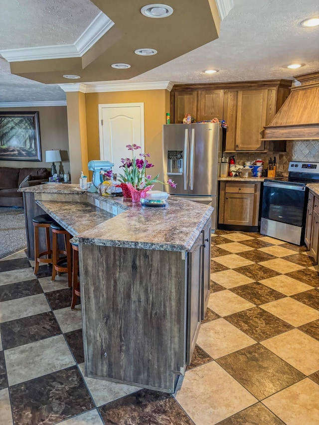 kitchen with crown molding, custom exhaust hood, recessed lighting, a raised ceiling, and appliances with stainless steel finishes