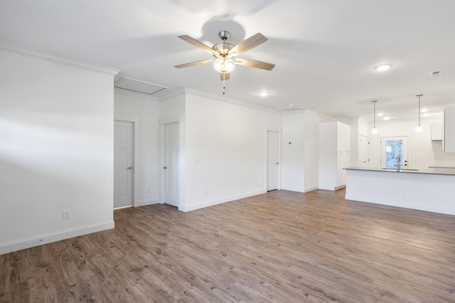 unfurnished living room with wood-type flooring, ceiling fan, crown molding, and sink