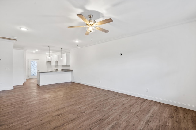 unfurnished living room with ceiling fan, wood-type flooring, and ornamental molding