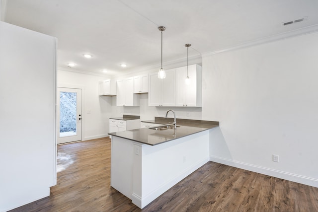 kitchen with white cabinetry, sink, dark hardwood / wood-style floors, kitchen peninsula, and decorative light fixtures