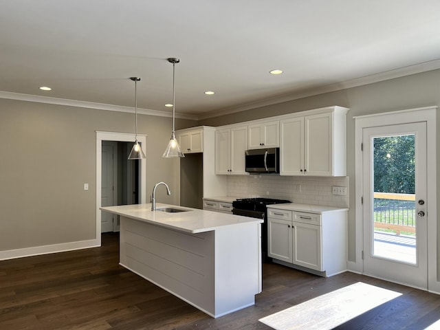 kitchen featuring light countertops, stainless steel microwave, a kitchen island with sink, a sink, and white cabinetry