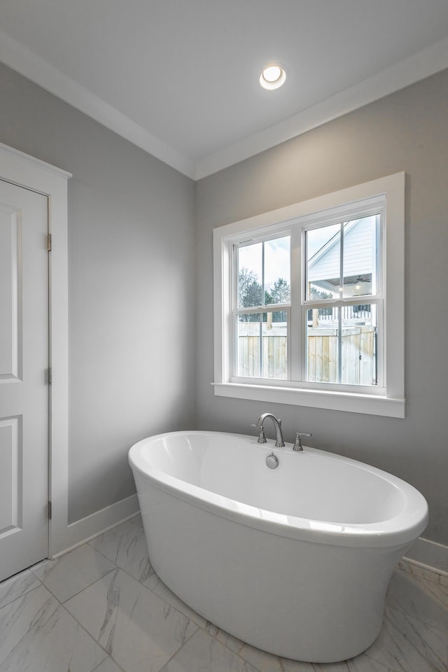 full bath with marble finish floor, baseboards, ornamental molding, and a freestanding bath