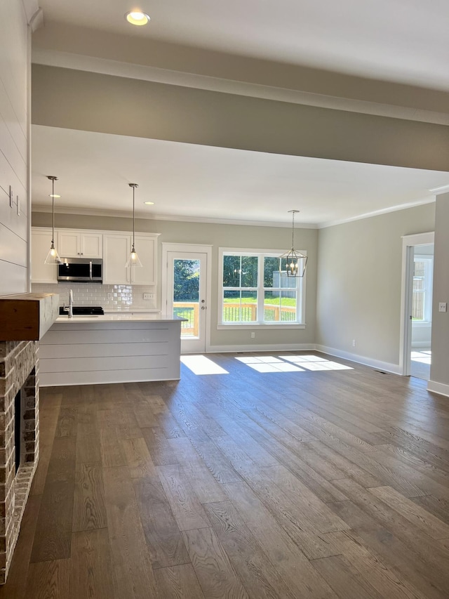 unfurnished living room with a brick fireplace, baseboards, dark wood-type flooring, and ornamental molding