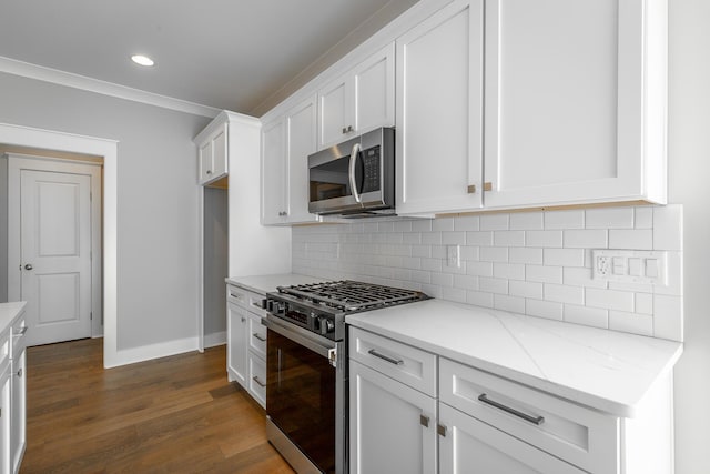 kitchen with dark wood finished floors, stainless steel appliances, backsplash, white cabinetry, and light stone countertops