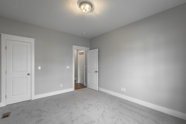 unfurnished bedroom with carpet flooring, visible vents, and baseboards