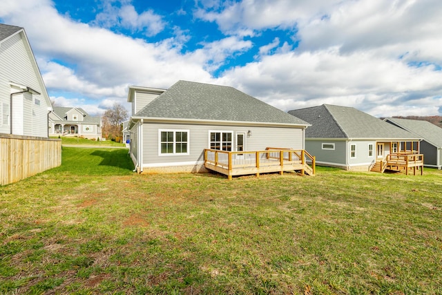 back of property with a residential view, roof with shingles, a lawn, and a wooden deck