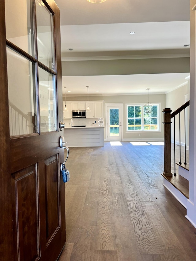 interior space featuring stairs, ornamental molding, light wood-type flooring, and baseboards