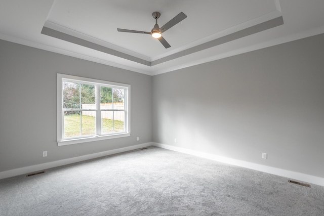 carpeted spare room featuring a raised ceiling, visible vents, and baseboards