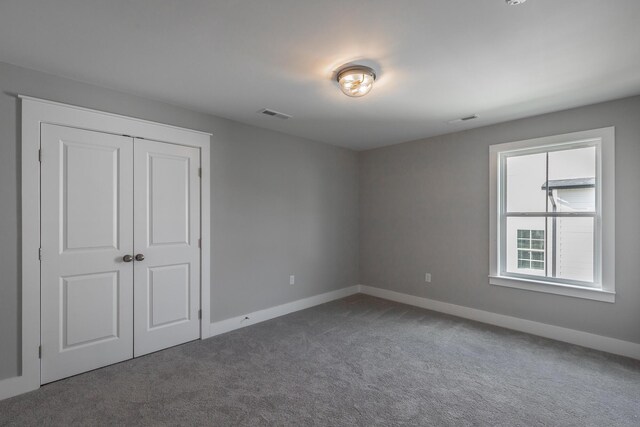 unfurnished bedroom with carpet, a closet, visible vents, and baseboards