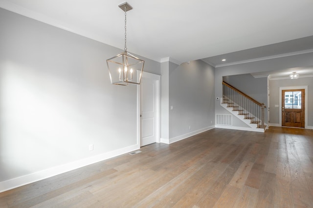 empty room with baseboards, stairway, wood finished floors, and ornamental molding