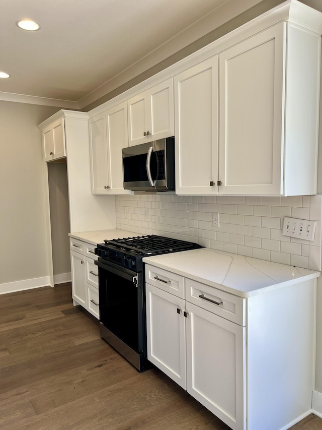 kitchen with stainless steel microwave, black range with gas cooktop, backsplash, and white cabinetry