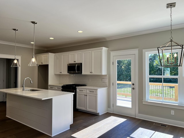 kitchen with stainless steel microwave, a sink, visible vents, white cabinets, and an island with sink