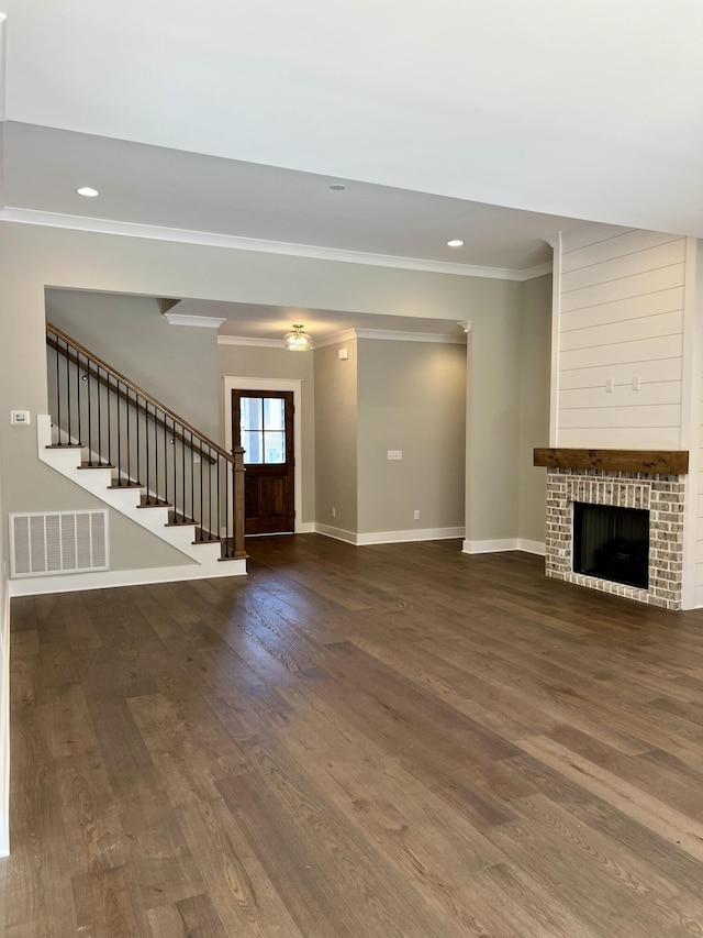 unfurnished living room featuring crown molding, visible vents, wood finished floors, baseboards, and stairs