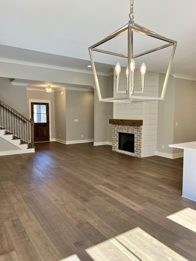 unfurnished living room featuring baseboards, dark wood-type flooring, stairs, a fireplace, and a notable chandelier