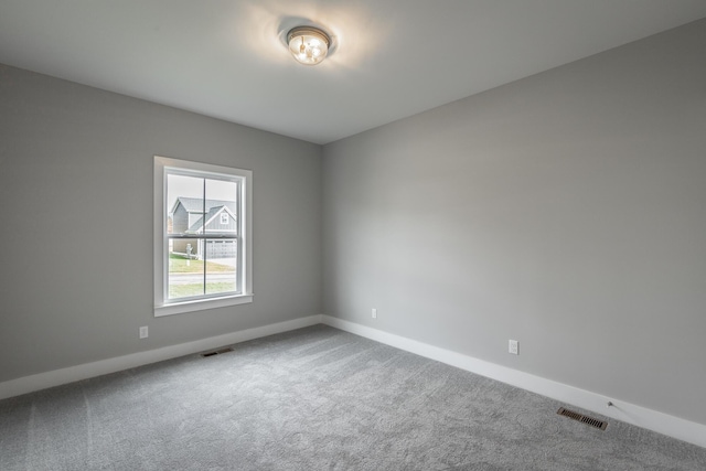 carpeted empty room featuring visible vents and baseboards