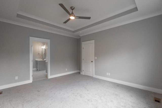 unfurnished bedroom with ornamental molding, a tray ceiling, visible vents, and light carpet