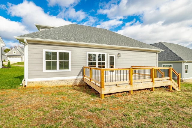 rear view of house featuring a shingled roof, a lawn, and a wooden deck