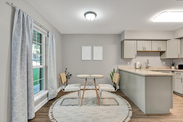 kitchen featuring wood-type flooring, gray cabinets, light stone counters, and a wealth of natural light