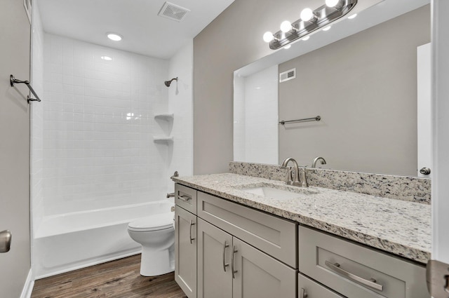 full bathroom featuring tiled shower / bath, hardwood / wood-style floors, vanity, and toilet