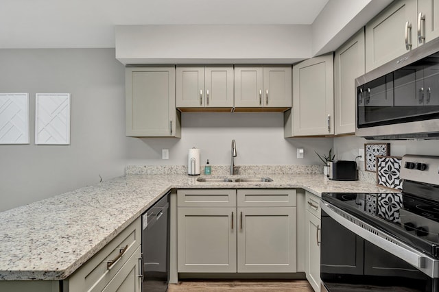 kitchen featuring gray cabinetry, light stone counters, sink, and appliances with stainless steel finishes