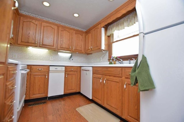 kitchen with backsplash, light hardwood / wood-style flooring, white appliances, and sink