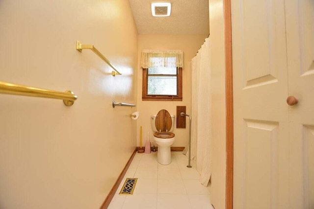 bathroom with tile patterned flooring, a textured ceiling, toilet, and walk in shower