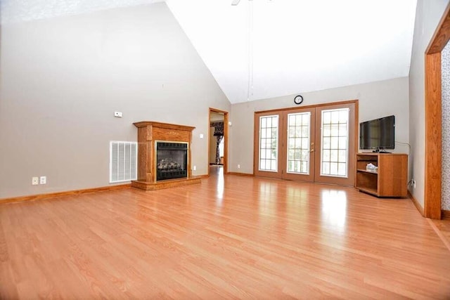 unfurnished living room with high vaulted ceiling and light hardwood / wood-style floors