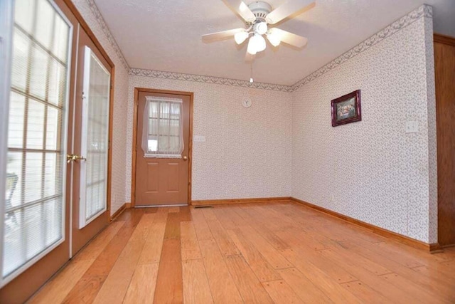 spare room featuring french doors, light hardwood / wood-style floors, and a healthy amount of sunlight