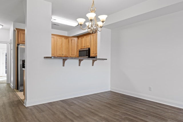 kitchen featuring a breakfast bar area, appliances with stainless steel finishes, kitchen peninsula, pendant lighting, and an inviting chandelier