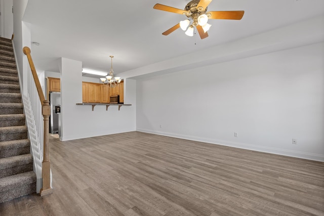 unfurnished living room featuring light hardwood / wood-style floors and ceiling fan with notable chandelier