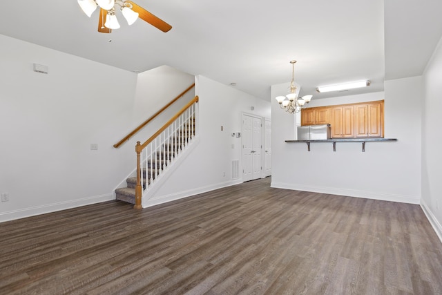 unfurnished living room with ceiling fan with notable chandelier and dark hardwood / wood-style floors