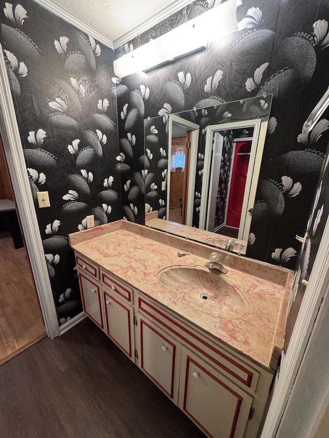 bathroom featuring wood-type flooring, vanity, crown molding, and a textured ceiling