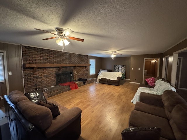 living room with ceiling fan, a brick fireplace, a textured ceiling, and hardwood / wood-style flooring