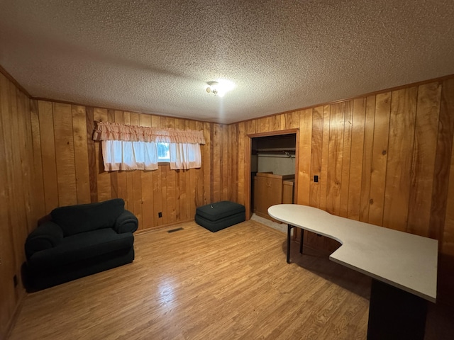 sitting room with wood-type flooring, wood walls, and a textured ceiling