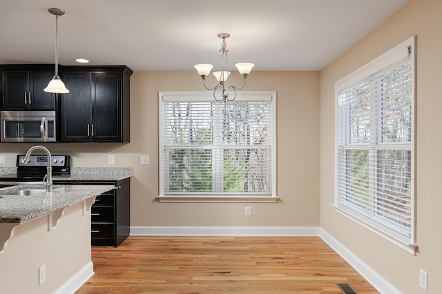 kitchen featuring light hardwood / wood-style flooring, stainless steel appliances, decorative light fixtures, and an inviting chandelier