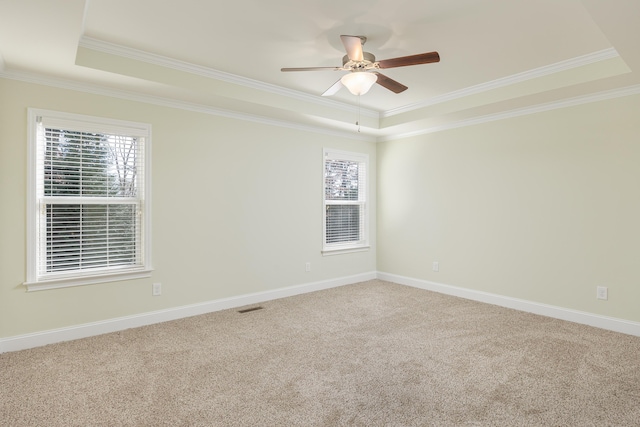 carpeted empty room with ceiling fan, crown molding, and a tray ceiling