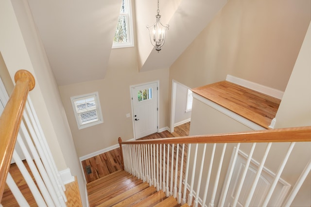 staircase with hardwood / wood-style floors, an inviting chandelier, and a high ceiling