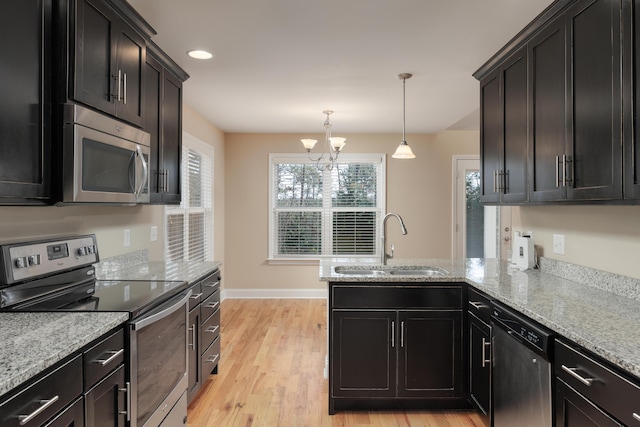 kitchen featuring sink, light hardwood / wood-style flooring, light stone counters, stainless steel appliances, and a chandelier