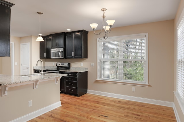 kitchen featuring a kitchen bar, appliances with stainless steel finishes, sink, decorative light fixtures, and an inviting chandelier