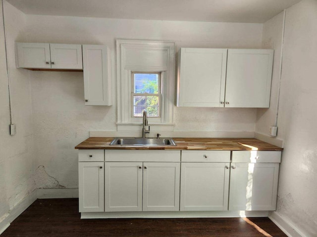 kitchen with sink, white cabinets, dark wood-type flooring, and wood counters