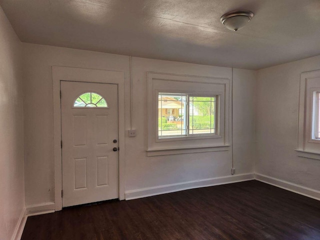 foyer entrance with dark wood-type flooring and a textured ceiling