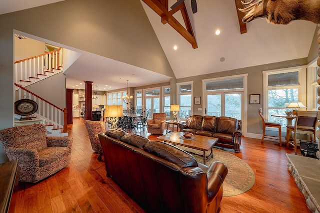 living room with a chandelier, high vaulted ceiling, stairway, hardwood / wood-style floors, and decorative columns