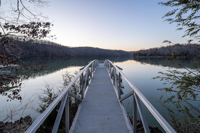 view of dock with a water view and a wooded view