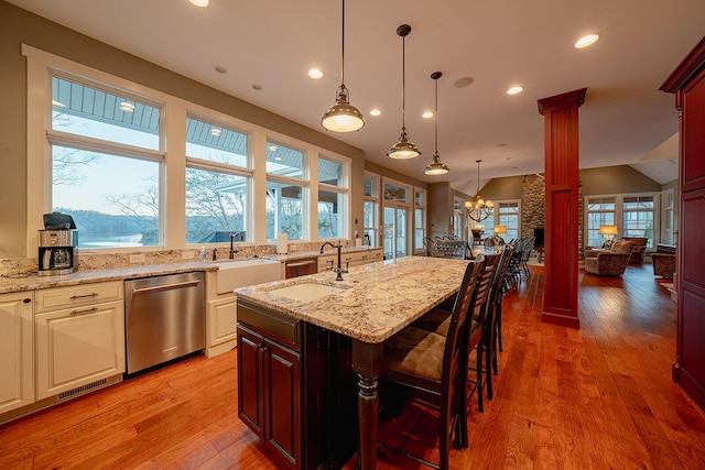 kitchen with dishwasher, a sink, light wood-style flooring, and ornate columns