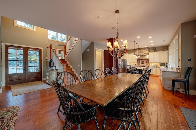 dining room featuring french doors, a notable chandelier, recessed lighting, stairway, and hardwood / wood-style flooring