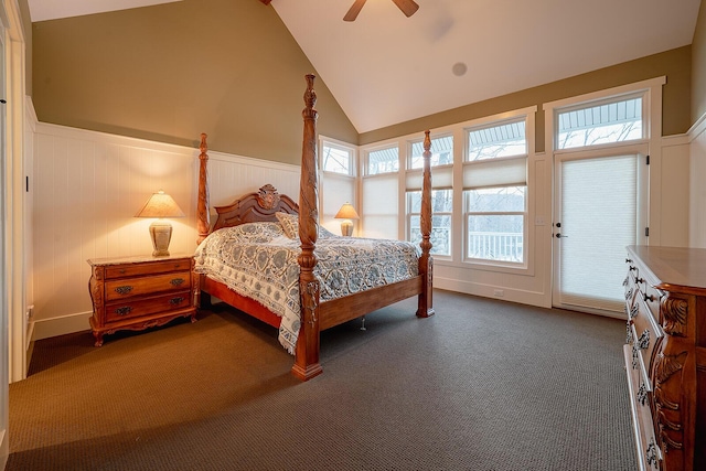 bedroom with ceiling fan, high vaulted ceiling, dark colored carpet, and wainscoting