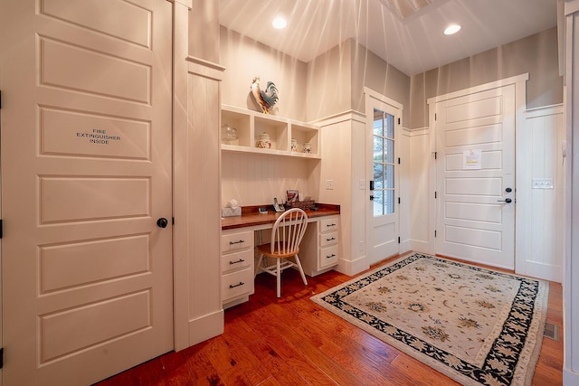 entryway featuring recessed lighting, a wainscoted wall, a decorative wall, built in study area, and dark wood finished floors